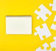 open notebook on a yellow background, next to large blank puzzles photo