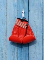 red leather boxing gloves hang on a nail photo