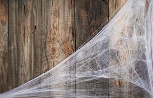 white spider web in the corner of the composition, gray wooden background from old boards photo