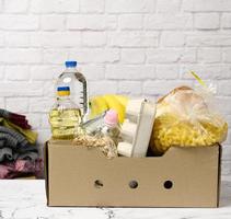 caja de cartón con varios productos, frutas, pasta, aceite de girasol en una botella de plástico y conservación foto