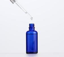 botella de vidrio azul con pipeta para cosméticos, aceites y suero. publicidad y promoción de productos foto