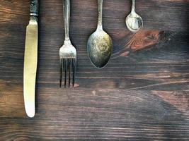 cuchillo, tenedor y cuchara sobre un fondo de madera marrón foto