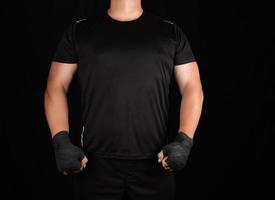 adult athlete in black uniform is standing in a rack with strained muscles photo