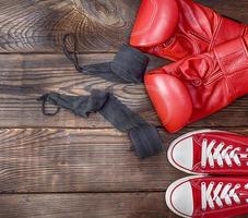 par de zapatillas textiles rojas y guantes de boxeo de cuero rojo foto