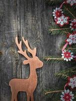 Toy  deer with decorated fir branches on a gray wooden surface photo