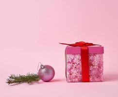caja de regalo rosa con lazo, rama de abeto verde y bola rosa decorativa foto