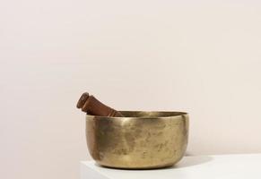 copper singing bowl and wooden clapper on a white table. Musical instrument for meditation, relaxation, various medical practices related to biorhythms photo