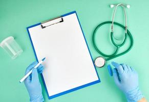 mano femenina con guantes estériles azules y estetoscopio médico foto