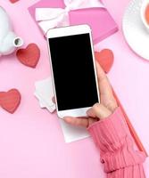 female hand holding white smart phone with blank black screen photo