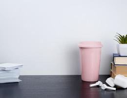 auriculares blancos inalámbricos con carga, taza de cerámica rosa con café foto