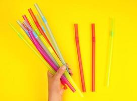 female hand holding multicolored plastic cocktail tubes photo