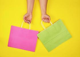 two hands holding paper shopping bags on a yellow background photo