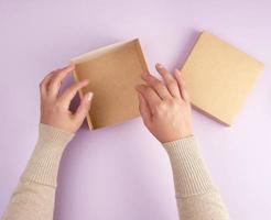 girl opens a brown square box on a purple background photo