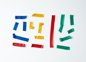 set of torn multicolored rubber pieces of electrical tape glued to a white background photo