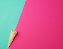 empty conical baked waffle cup on a green-pink background, place for text photo