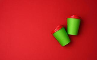 two green paper cups with a plastic lid on a red background, top view photo