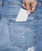hand sticks an empty paper business card into the back pocket of the jeans photo