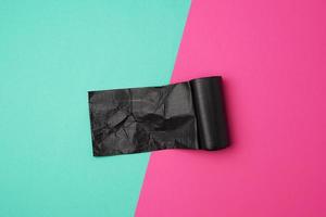 twisted roll with black garbage bags on a colored background photo