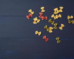 raw pasta in the form of bows on a blue wooden background, top view photo