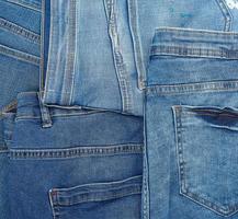 Lots of blue classic jeans stacked chaotically, back pocket photo