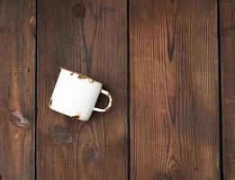 white metal mug with rust on a brown wooden background photo