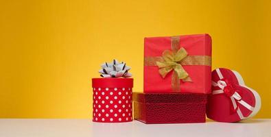 A stack of gift boxes wrapped in colorful paper on a yellow background. Happy Holidays photo