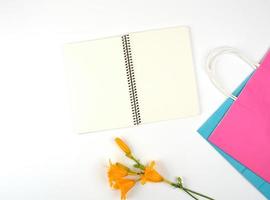 cuaderno abierto con hojas blancas en blanco y bolsas de compras de papel multicolor foto