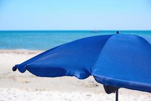 open blue textile beach umbrella on a sandy seashore photo
