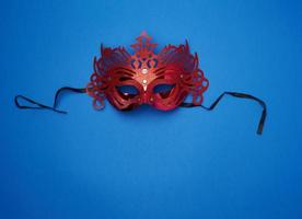 máscara tallada roja femenina con lazos negros sobre un fondo azul oscuro foto