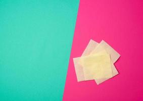 pieces of soft yellow toilet paper on a green-pink background photo