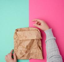 two female hand holding open brown paper bag for food packaging with greasy stains photo