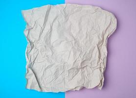 trozo de papel gris arrugado sobre un fondo de color, vista superior foto