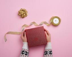 female hand holds a red box and golden ribbon, concept of congratulations photo