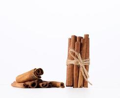 dry cinnamon sticks tied with a rope on a white background photo