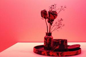 Dark red roses in vase and candle on a white table against pink wall. Zen, relax, wellness concept. Natural composition for meditation. Valentines Day, Happy Women's Day, Mother's day. Space for text
