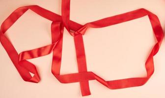 curled red satin ribbon on a beige background photo