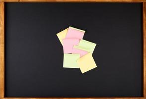 square multi-colored stickers hang on a black board photo