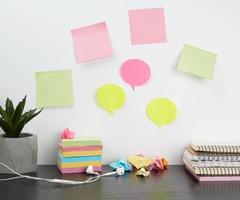 colored stickers attached to a white wall, on the table a stack of notepads photo