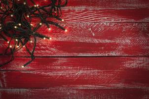 Christmas garland with small light bulbs on the red shabby wooden surface photo