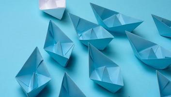 group of blue paper boats follow white against a light blue background. Strong leader concept, mass manipulation. Starting a business with a well-coordinated team, start-up photo