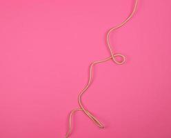 twisted golden cable in a textile winding on a pink background photo