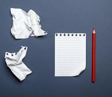 white blank sheets in a line from a notepad and red wooden pencil photo