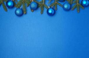 green spruce branches, blue shiny Christmas balls on a blue background, festive backdrop photo