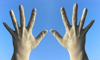 Two female hands in the dirt and dust from the splayed fingers against the blue sky photo