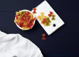 raw pasta in the form of bows in a wooden round plate and white textile napkin photo