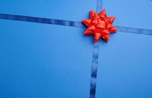 blue silk ribbon crossed on a dark blue background in the middle of a red bow photo