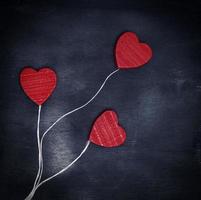 three red wooden hearts on a white string photo