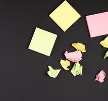 empty square multi-colored stickers hang on a black board photo