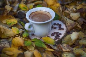 Cup of coffee among the yellow fallen leaves photo