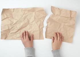 two hands tearing a sheet of brown craft paper photo